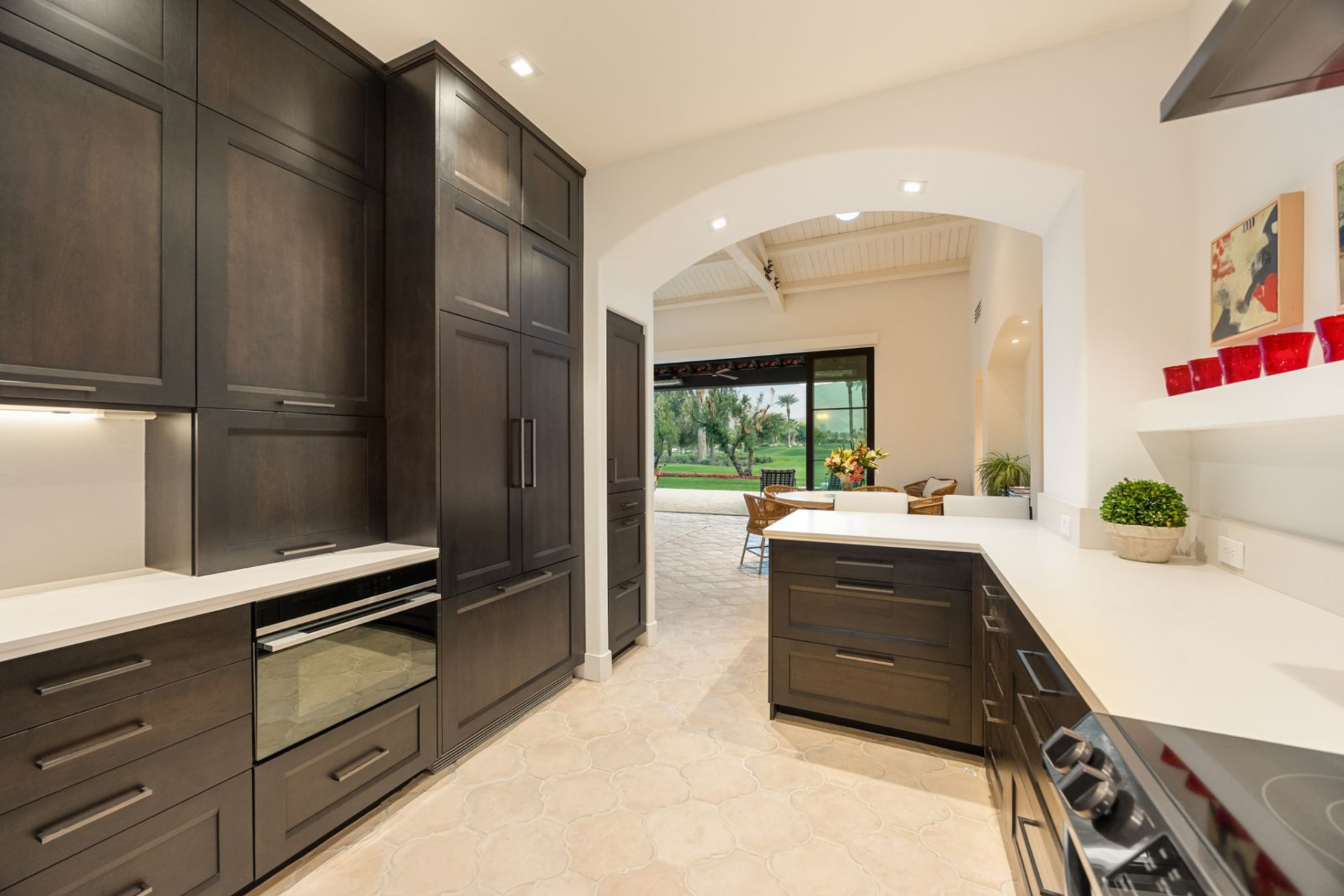 Just off the dining area, the kitchen shifts into a more streamlined workspace with dark DeWils cabinetry, Caesarstone counters, and a wide arched opening that keeps the room connected to the home’s outdoor-facing living spaces.