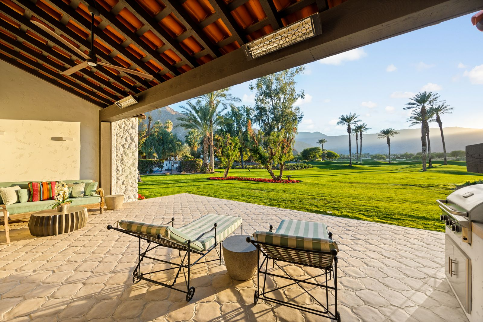 A covered terrace with exposed wooden beams and terra-cotta roofing provides a shaded spot to lounge, complete with a barbecue area for outdoor entertaining.