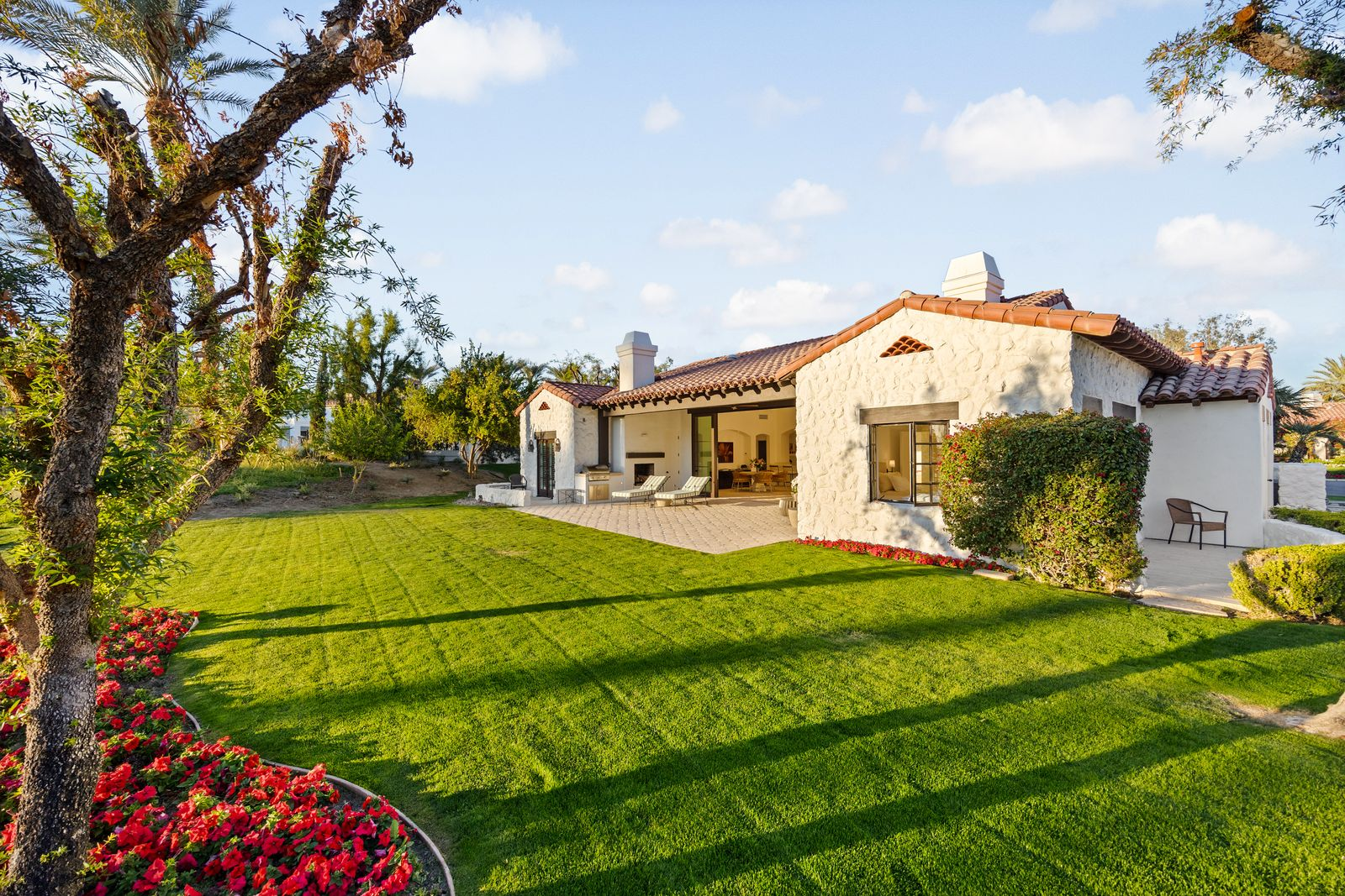 The backyard patio offers an uninterrupted connection to the lush greens of the golf course, framed by towering palm trees and distant mountains.