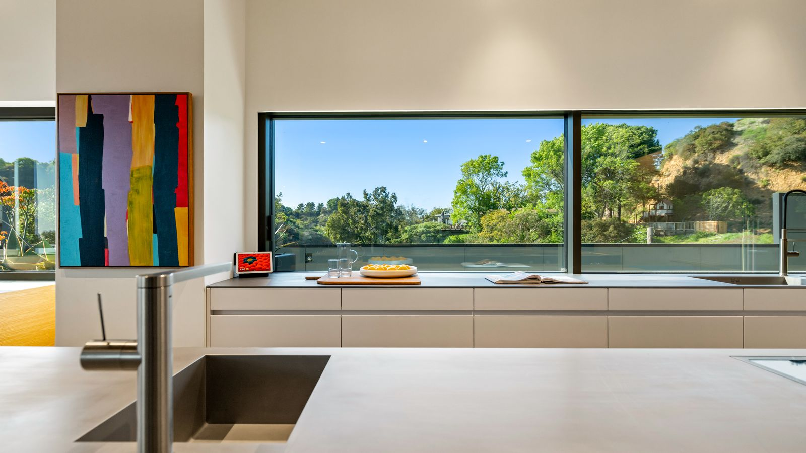 On the other side, a massive matte-finished island sits across from floor-to-ceiling cabinetry in matte black with integrated state-of-the-art appliances.