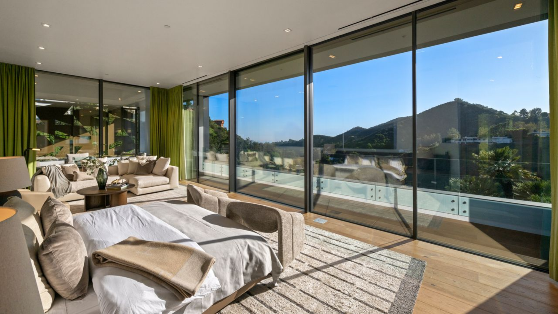 The bedroom is arranged parallel to a wall of floor-to-ceiling glass that opens to the terrace, with the bed positioned to face the view.