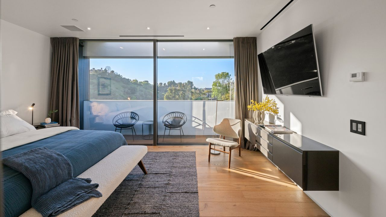 Inside, the layout is simple and efficient, with the bed along one wall, a wall-mounted TV opposite it, and a pair of chairs outside.