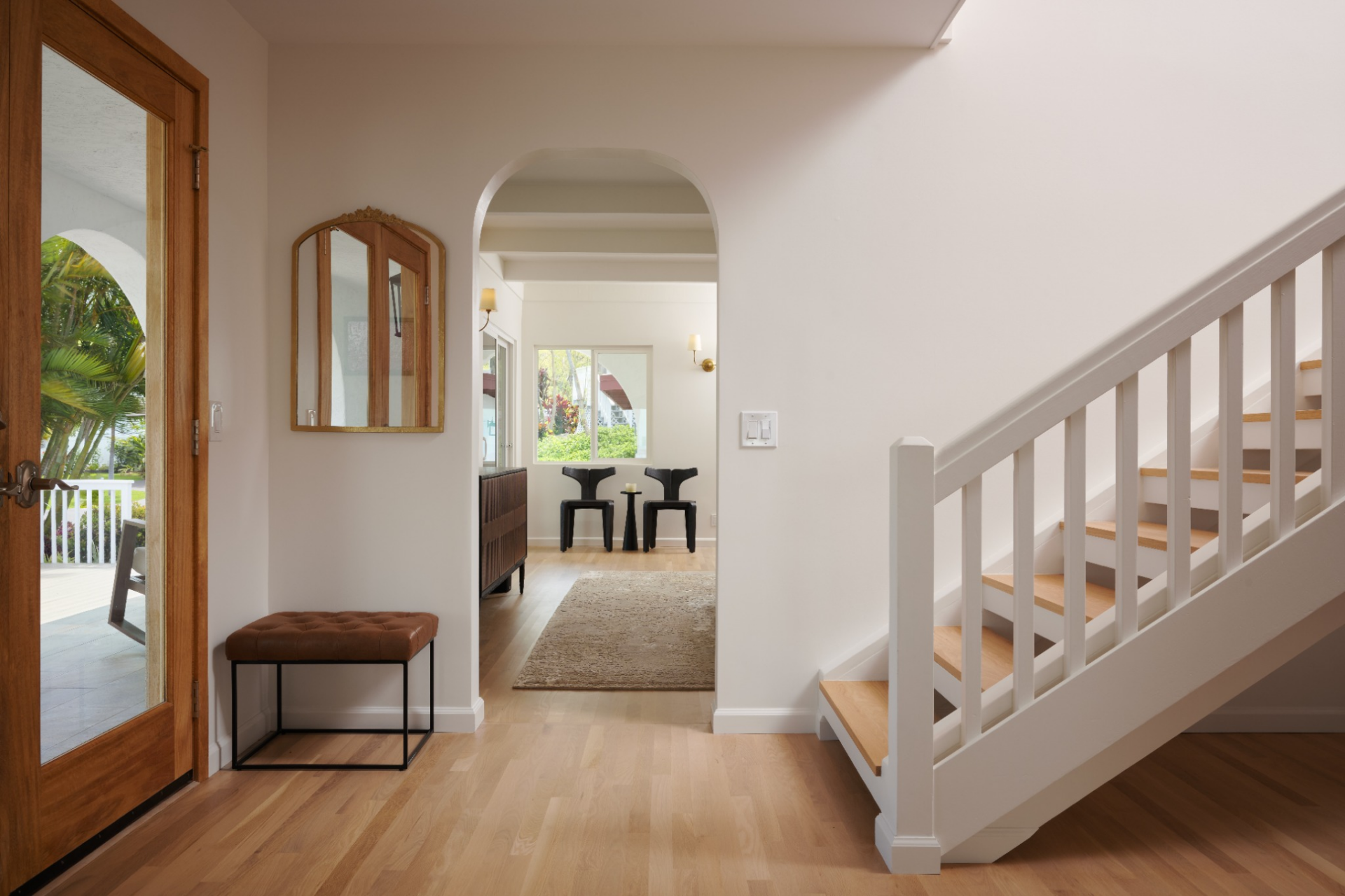 The layout opens with the staircase positioned along one side, next to arched openings and glass doors that frame views of the surrounding landscape.