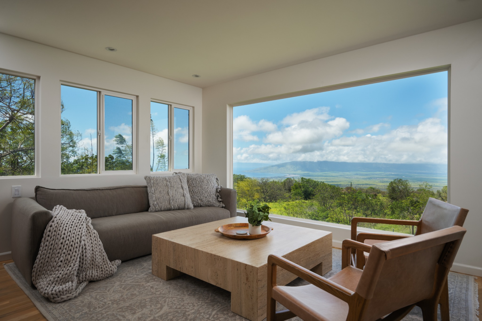 At the far end, the living area is positioned around the landscape, with a large picture window pulling the Maui views directly into the room. 