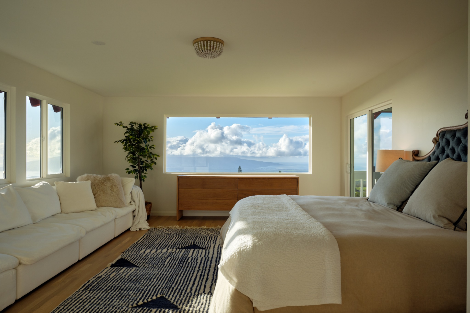 A sitting area lines one wall across from the bed, with a wide picture window looking out toward the mountains between them. 
