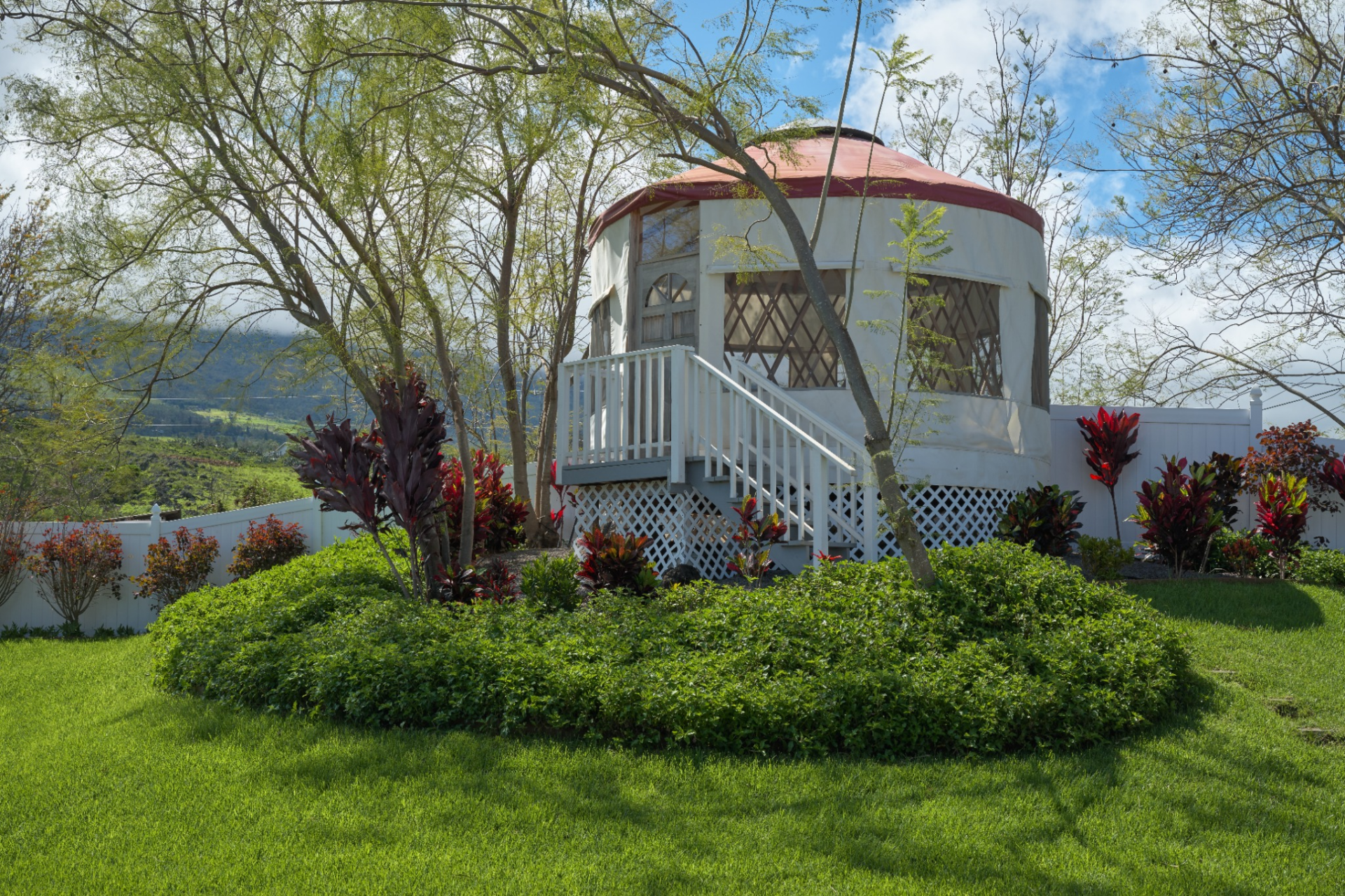 Placed at the front of the property, the custom yurt is accessed by a short staircase and surrounded by tropical plants.