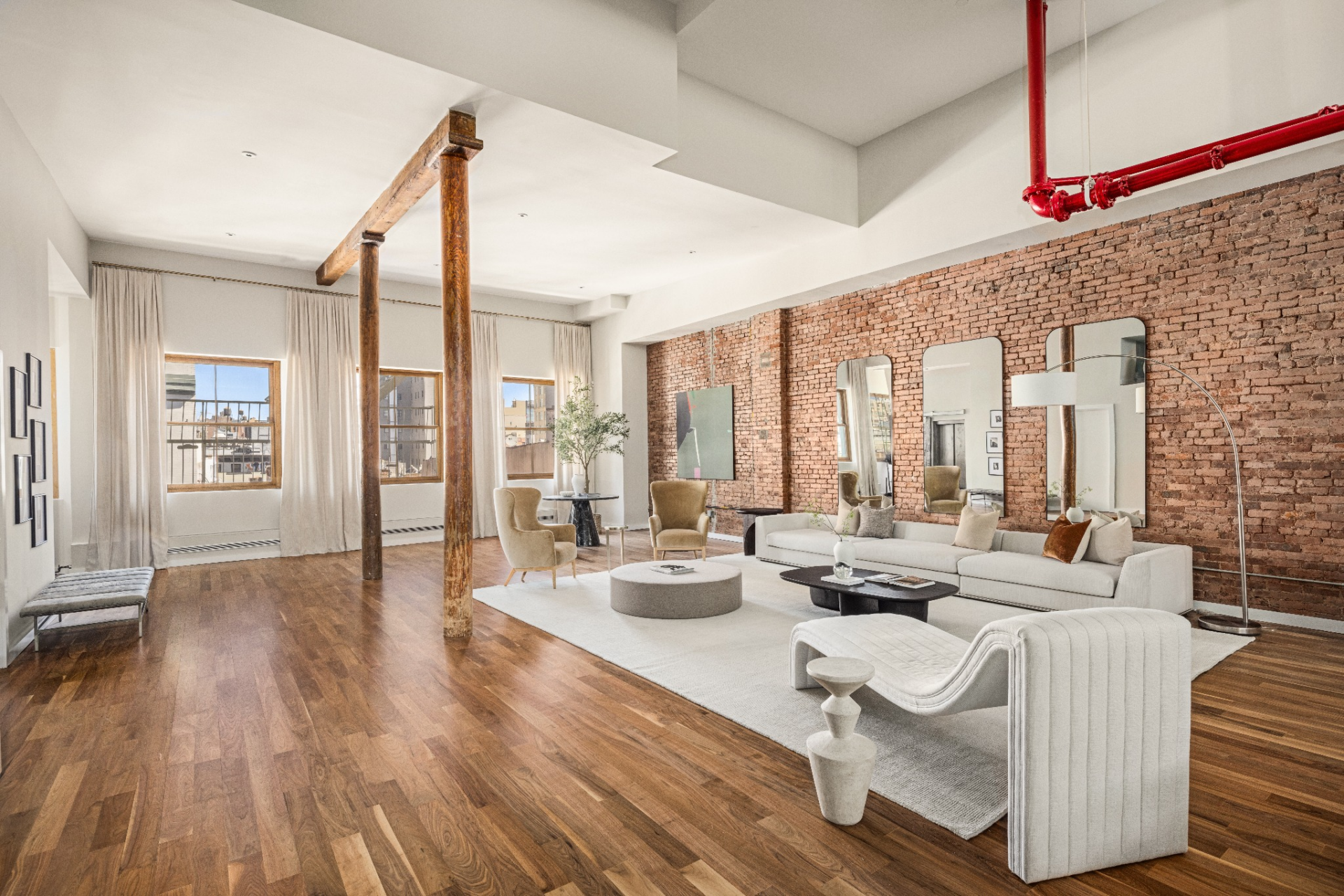 A low, neutral seating group sits atop an area rug, with sculptural lounge chairs and a curved chaise adding contrast.