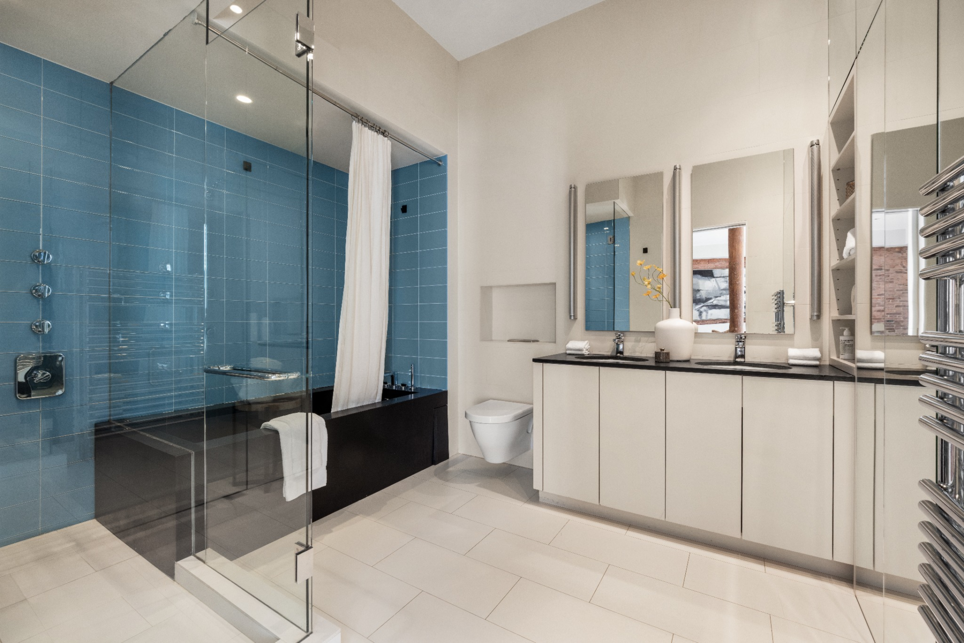 The suite continues with a bathroom featuring heated floors that lead to a soaking tub set alongside a separate shower, all backed by blue tile.
