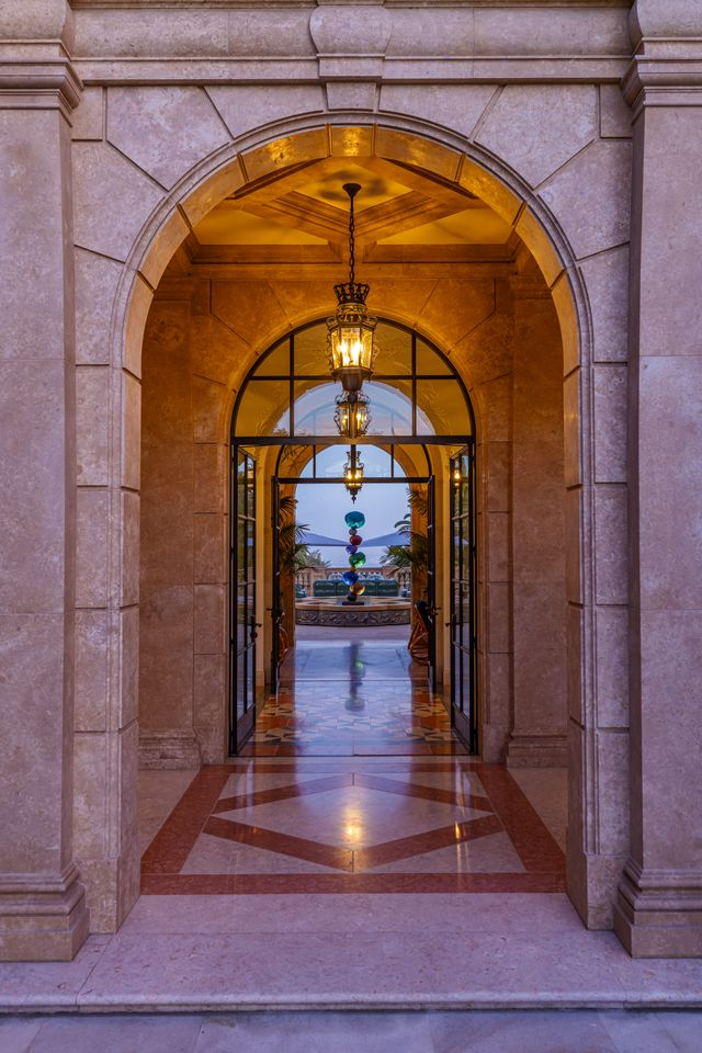 Stepping beneath the stone arch, the ceiling lowers slightly and is finished in coffered stone, with a series of hanging lanterns aligned down the center, pulling you forward. 