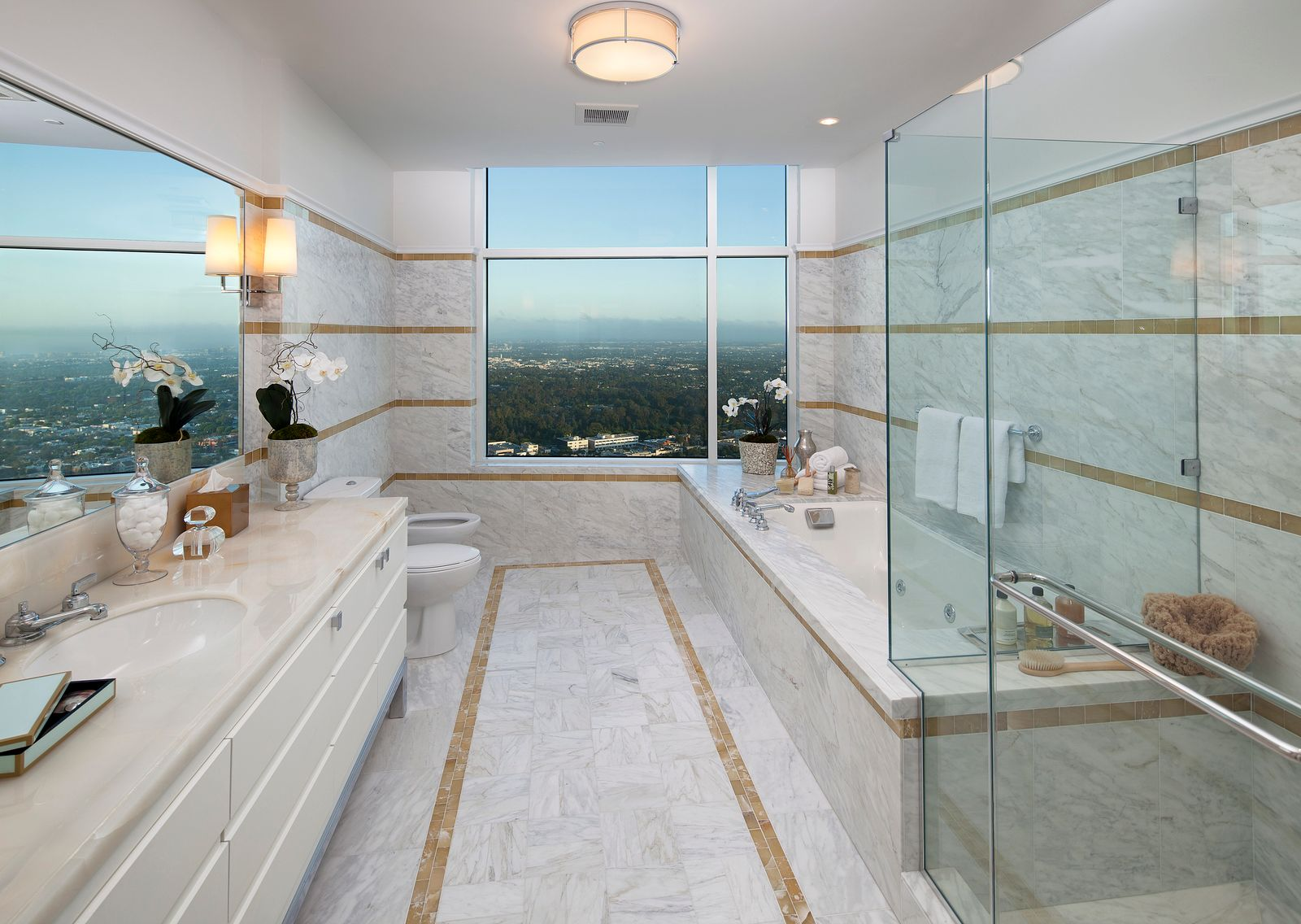 The suite's spa-style bathroom has a deep sense of calm, lined with marble surfaces across the glass-enclosed shower and soaking tub that sit across from the vanity. 