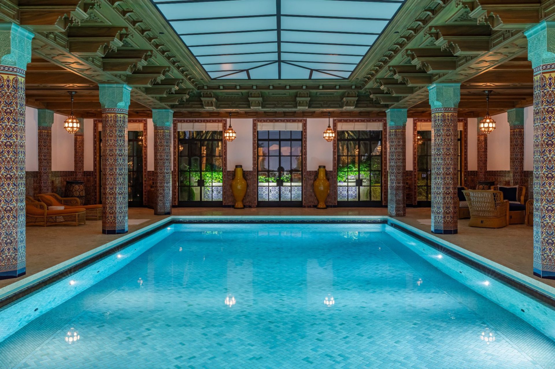 The indoor pool is one of the home’s most elaborate amenity spaces, framed by tiled columns, carved ceiling details, and a large skylight overhead. 