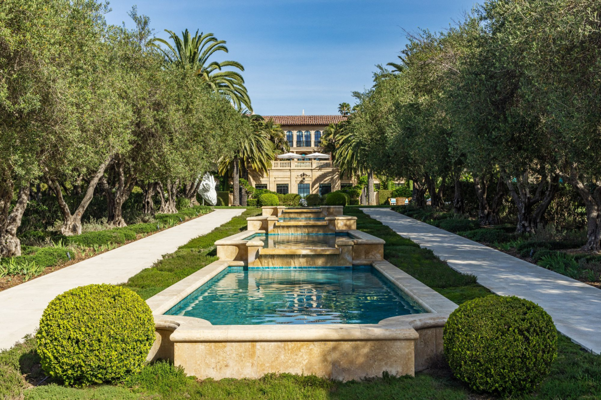Running through the middle of the grounds, a series of tiered stone fountains creates a linear water feature that draws the eye straight back toward the main house. 