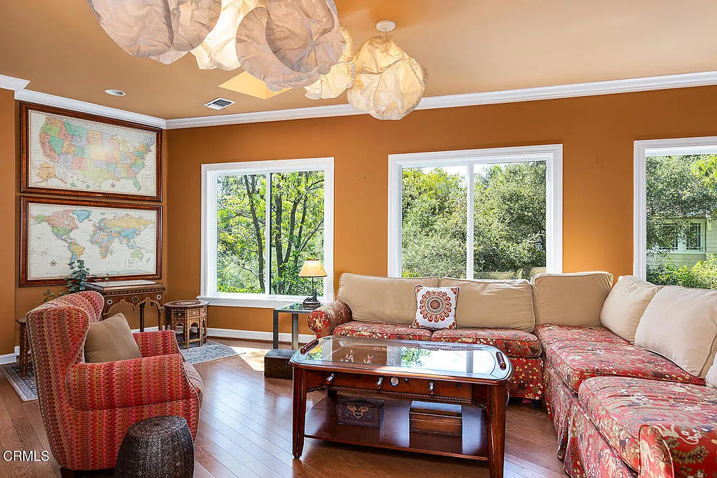 A large sectional wrapped in red patterned upholstery is paired with matching armchairs and a wood foosball coffee table at the center.