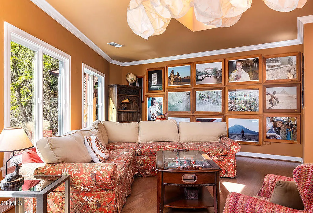 From the opposite angle, the room opens up to a full wall of framed travel photography, turning the seating area into a backdrop for personal memories.