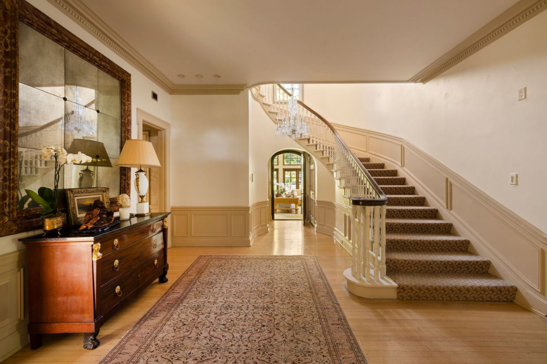 Inside, the house immediately introduces the period craftsmanship that defines it, from the original boiserie paneling wrapping the lower walls to the detailed crown moldings tracing the ceiling above. 