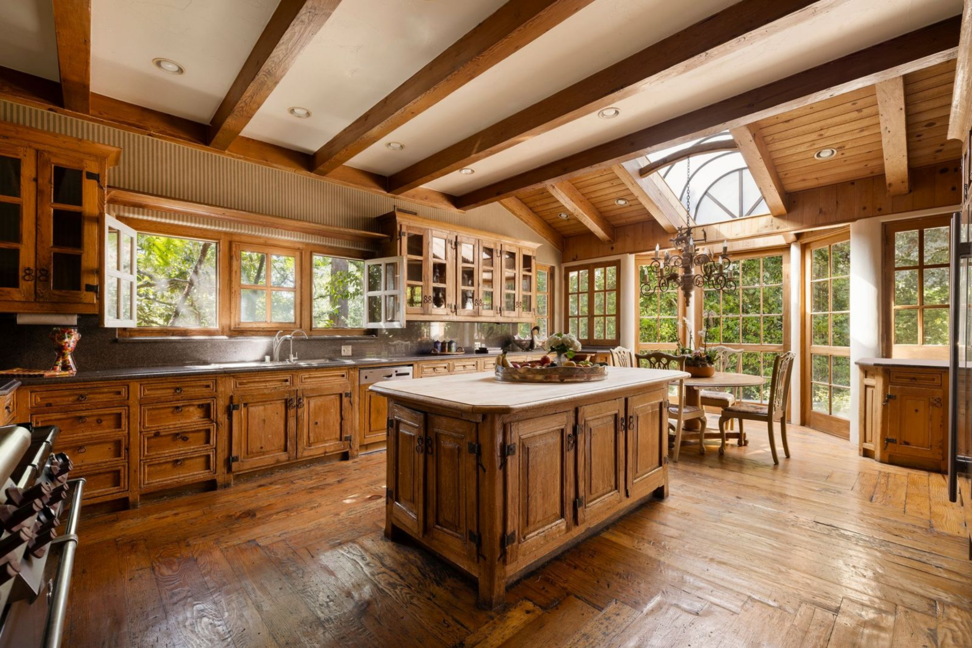 Down the hall, the kitchen shifts away from the home’s more formal front rooms and opens into a larger, more relaxed workspace built around wood cabinetry and garden-facing glass. 