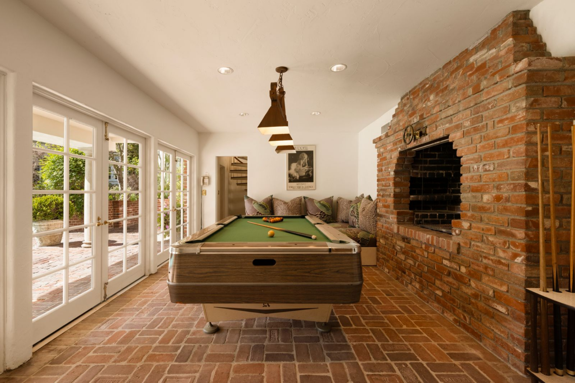 The detached guest house adds another layer to the property, beginning with a billiards room that opens through French doors on one side with a full brick fireplace along the other. 