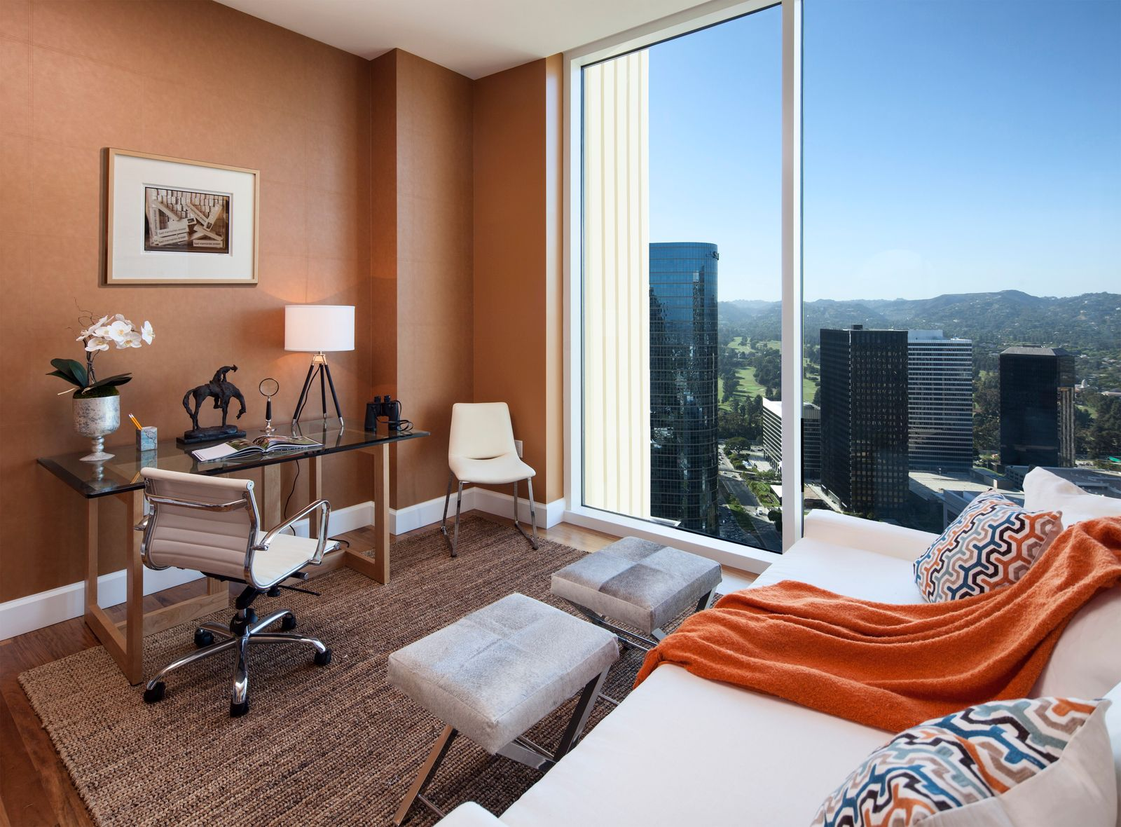 This study is placed within a burnt orange accent wall and full wall of glass overlooking Los Angeles.