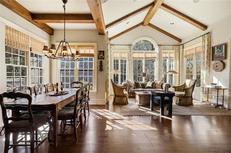 The living room continues directly into an open gathering space that combines a casual dining area with a sunlit lounge overlooking the property. 