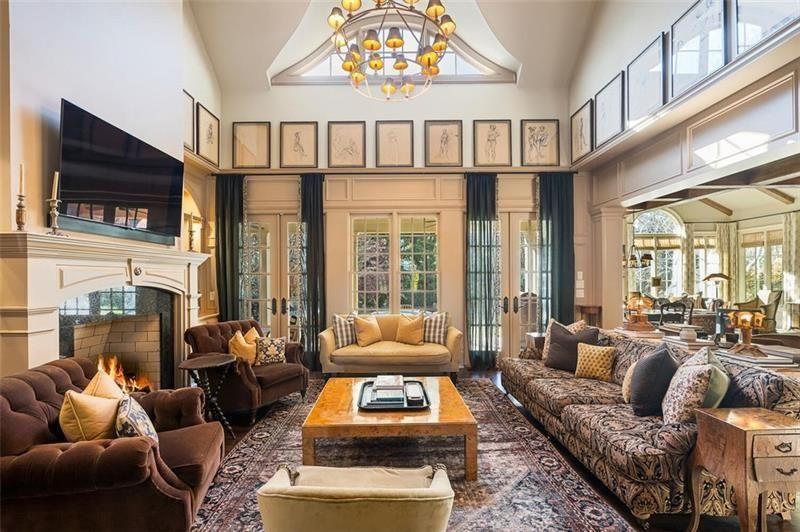 Despite its size, the room is arranged to feel comfortable and conversational, with layered rugs, deep upholstered seating, and antique-style wood tables spread throughout the space.