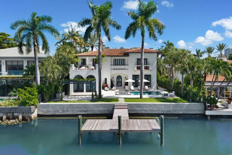 Waterfront mansion with a private dock extending from the backyard.