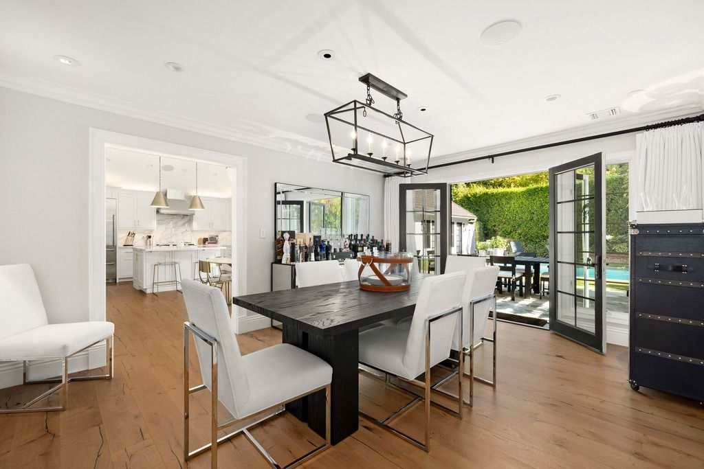 Next to the media room, the dining area consists of a dark wood dining table surrounded by upholstered chairs beneath a large lantern-style light fixture.