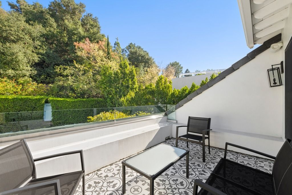 French doors next to the lounge open directly to a private balcony overlooking the surrounding greenery, bringing natural light deep into the room and extending the suite outdoors.