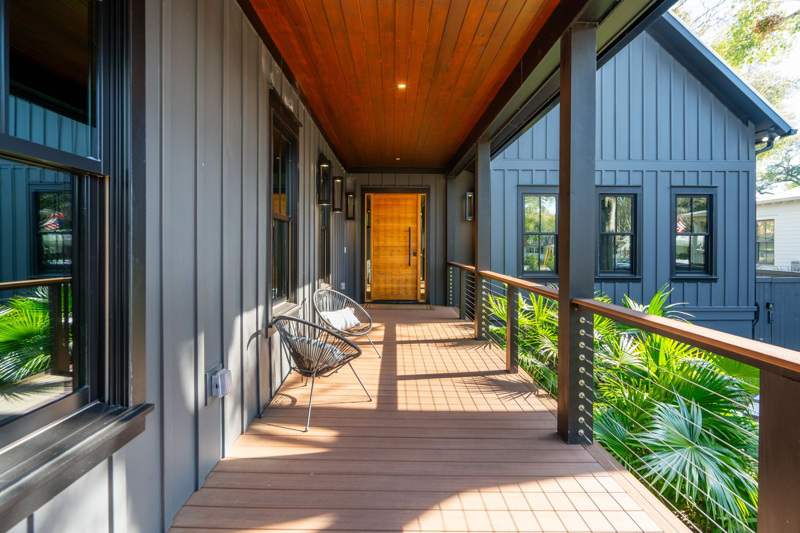 As you walk towards the white oak front door, black-framed windows run alongside the porch, while cable railings and tropical landscaping create a sense of openness.