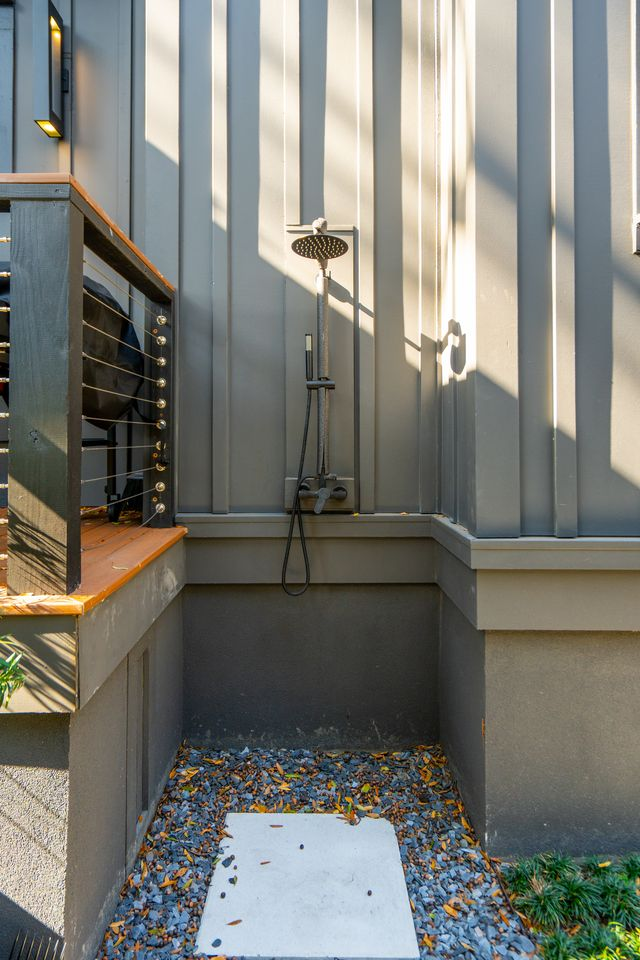 Hidden near the porch, the outdoor shower is built directly into the dark vertical siding with matte black fixtures that match the rest of the home’s modern detailing.
