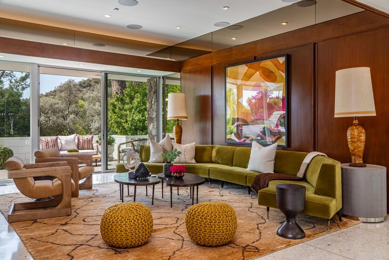 The room features a curved velvet sectional positioned around a low circular cocktail table, giving the space a conversational layout that feels designed for entertaining. 