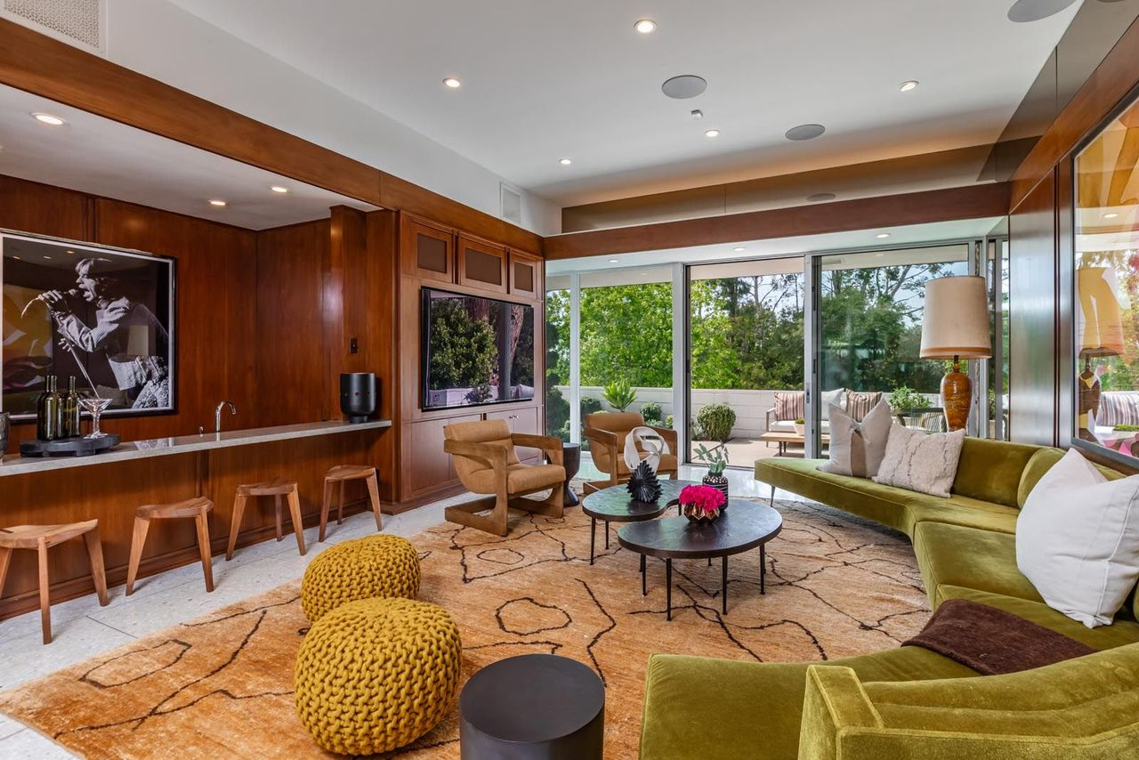 Along the far wall, a built-in bar and media center stretches across the room beneath recessed lighting, blending storage, display shelving, and serving space into the original architecture.