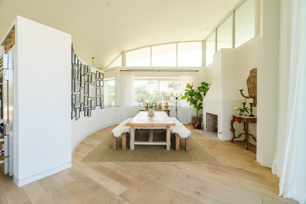 A long reclaimed wood dining table stretches through the center of the room beneath soaring ceilings and clerestory windows, with simple bench seating.