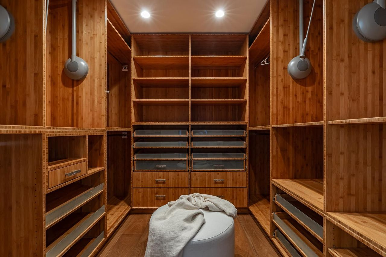 Next up is the closet, which is lined completely in wood cabinetry, varying from closed drawers and open shelving to hanging space.
