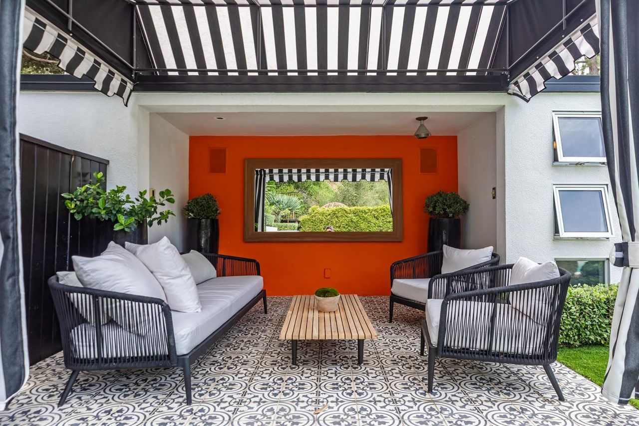 Across the yard, a striped poolside gazebo features patterned tile flooring, woven outdoor seating, and retractable drapes, creating a shaded lounge area tucked beside the pool deck.