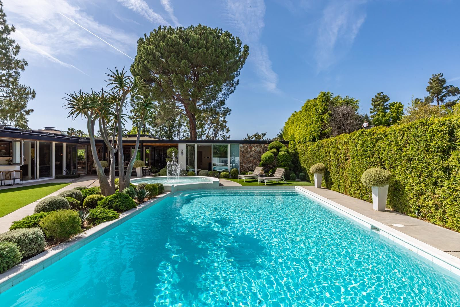 The pool itself sits in the center of the backyard with a geometric layout that complements the home’s horizontal lines and low-slung roofline.