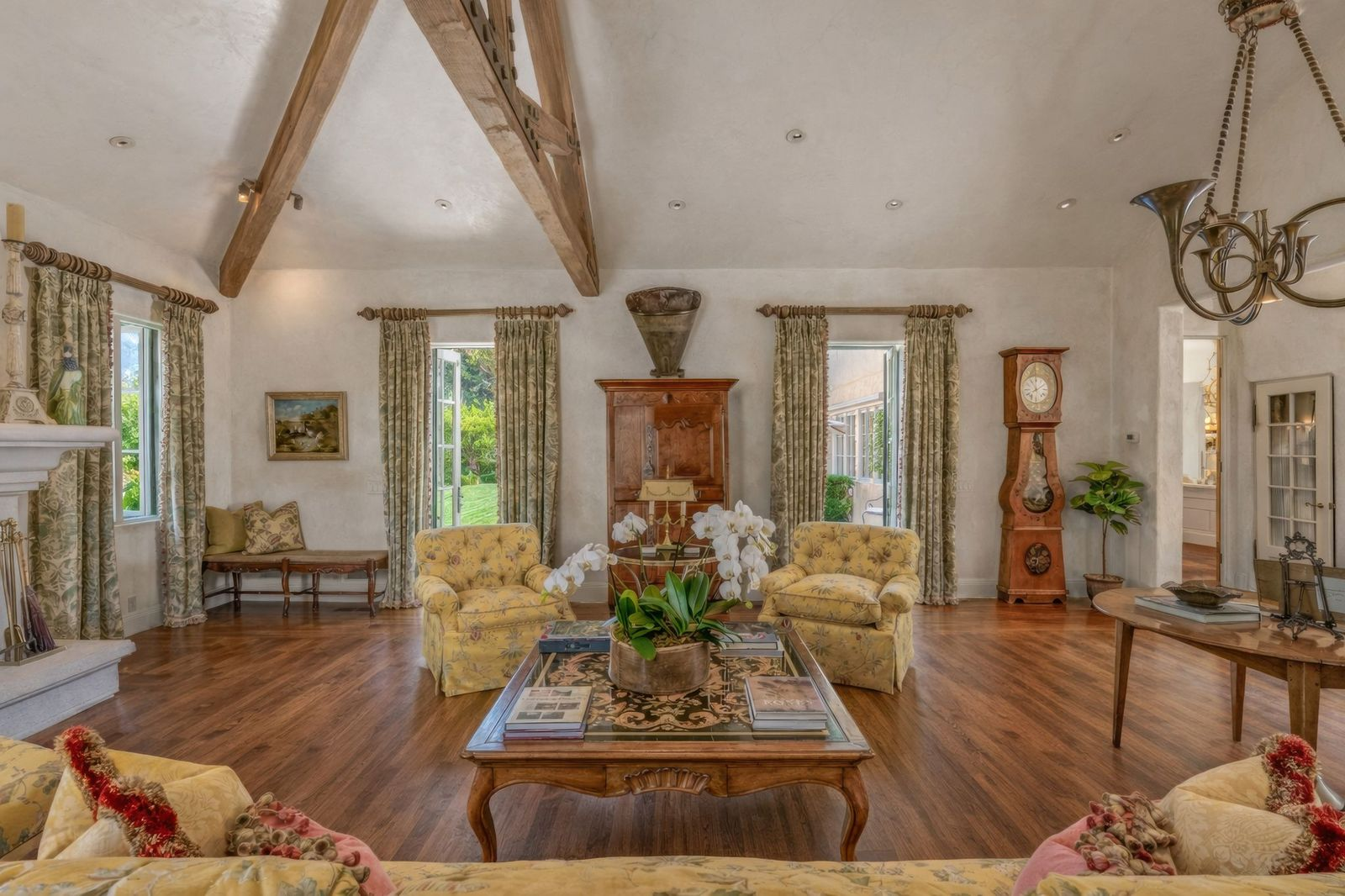 Large windows and French doors bring in natural light from multiple sides, while the open layout keeps the room visually connected back toward the foyer and surrounding spaces.
