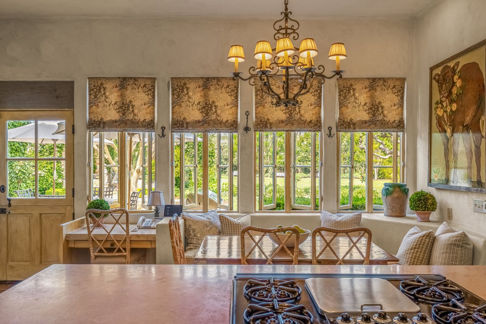 A built-in breakfast nook sits beneath a row of tall divided-light windows overlooking the grounds, bringing light directly into the center of the room.