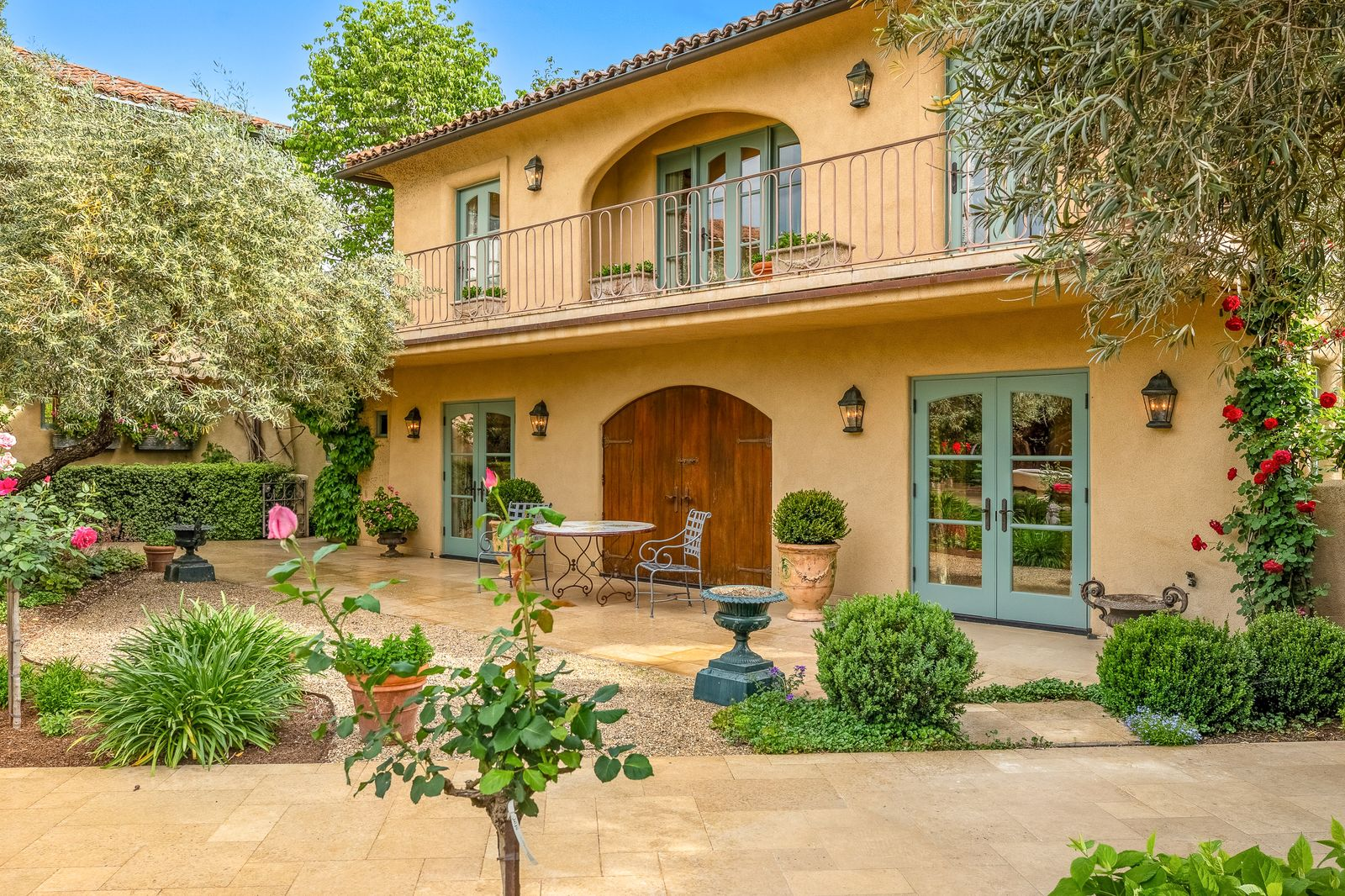 A two-story exterior that blends soft stucco walls, wrought-iron detailing, and French-inspired architecture.