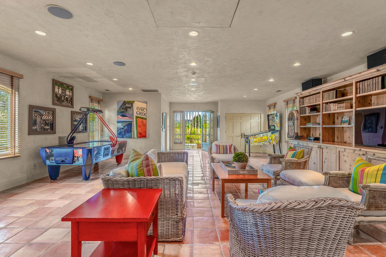 The long layout allows room for multiple seating areas alongside arcade-style entertainment, including an air hockey table and a pinball machine.
