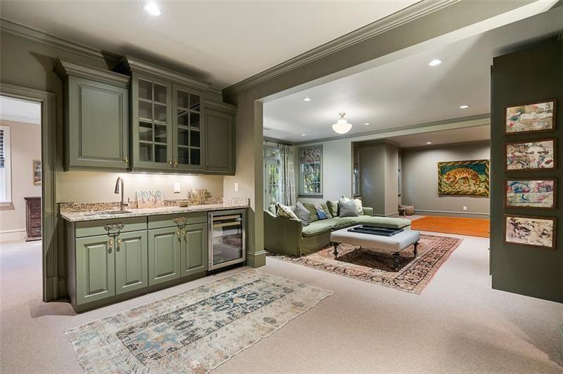 The main lower-level gathering area centers around a casual lounge with built-in cabinetry, a large sectional seating area, and a fully integrated wet bar tucked just off the side. 