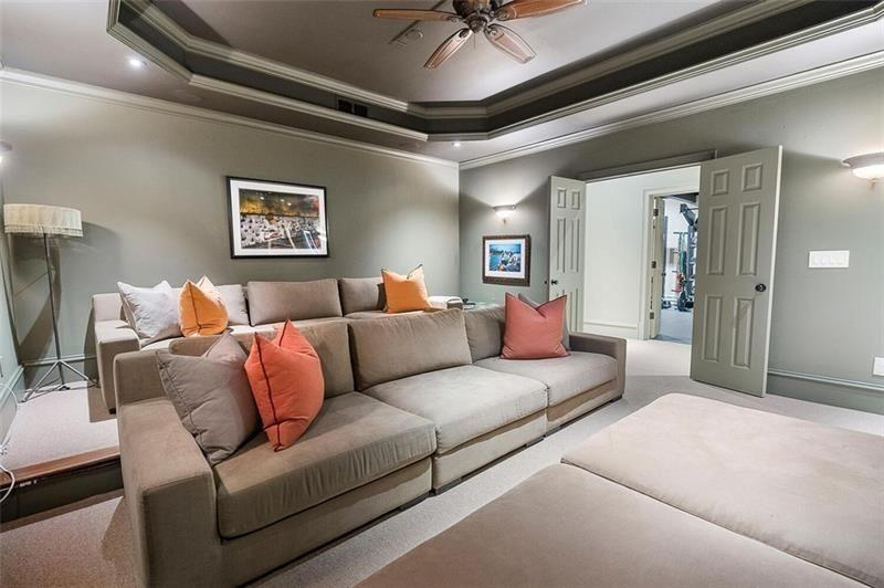 Nearby, the lower level also includes a dedicated movie theater designed with oversized sectional seating arranged directly toward the screen wall. 