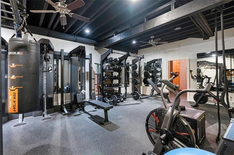 The wellness area is built around a fully equipped gym consisting of strength machines, cardio equipment, free weights, and rubberized flooring beneath exposed dark ceiling beams. 