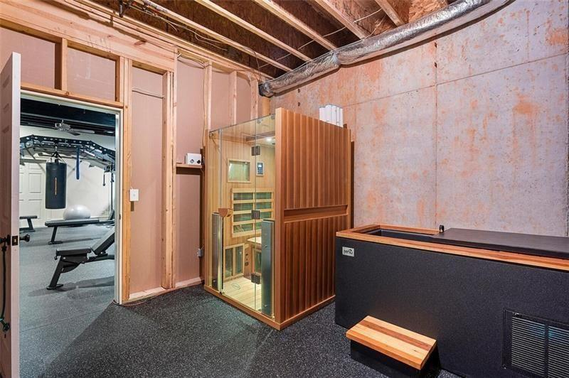Attached to the workout space is a recovery area featuring both a sauna and cold plunge setup, turning the lower level into a complete fitness zone.