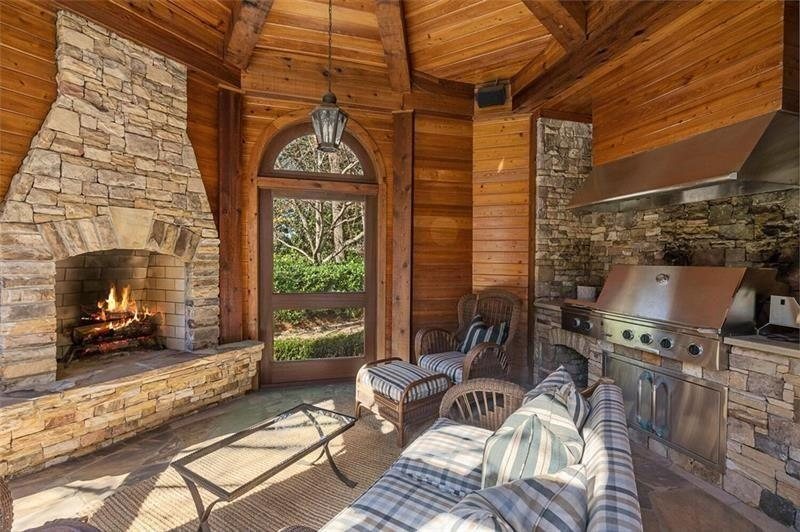 Wrapped almost entirely in arched windows and glass doors, the circular space features a large stone fireplace and a built-in grilling station. 