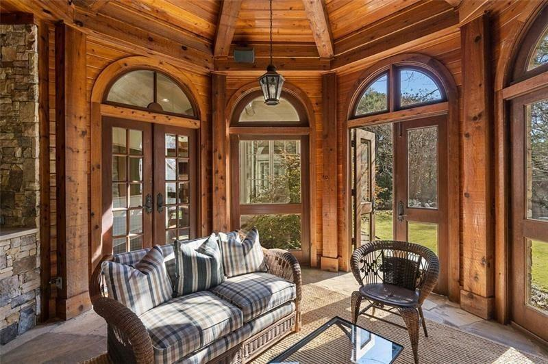 Wicker seating arranged beneath the exposed timber ceiling creates a casual lounge area positioned between the fire and the garden views outside.
