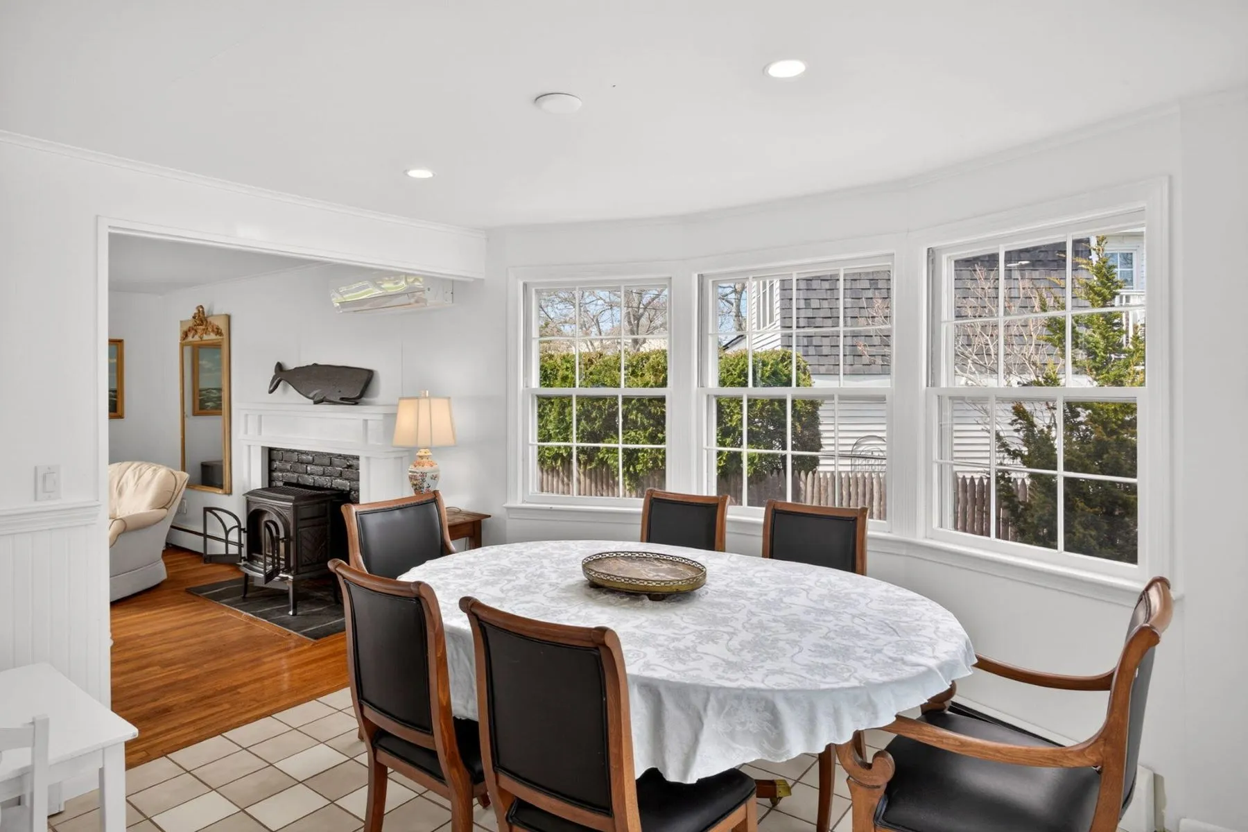 In the next room, the dining area continues the home’s bright coastal style with a wall of bay windows wrapping the round table and dark wood chairs set up for more formal meals.