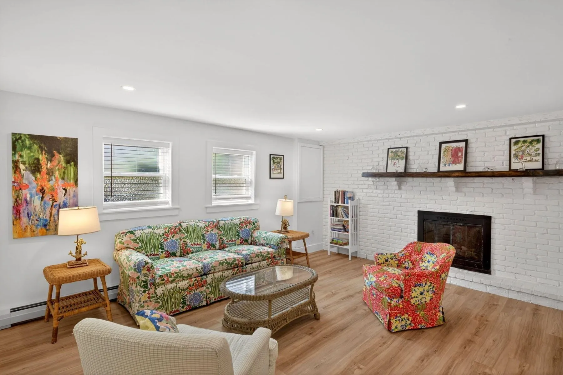 Colorful furniture sit next to a white brick wall with a black fireplace in the center.