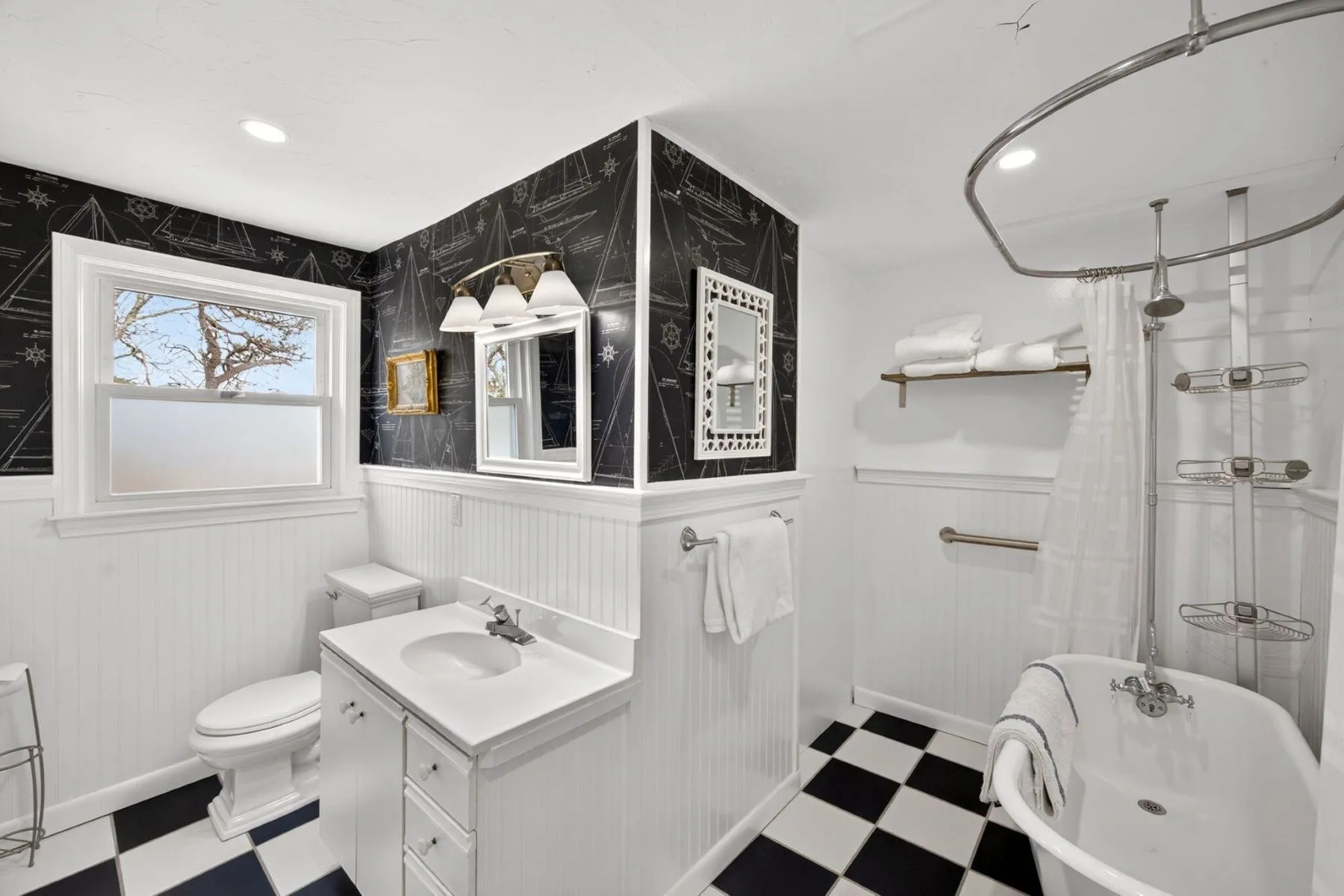 One of the more unique bathrooms combines black-and-white checkerboard flooring with dark wallpaper printed in sailboat sketches and nautical motifs. 