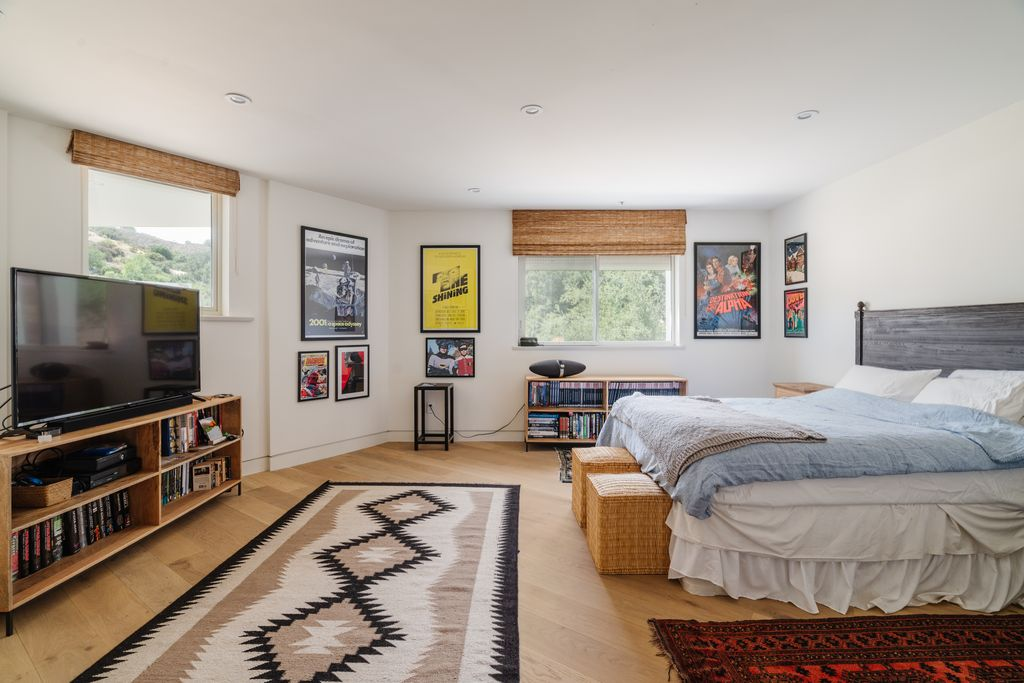 Another bedroom takes on a more playful character, filled with framed film posters and built-in shelving lined with books and collectibles. 