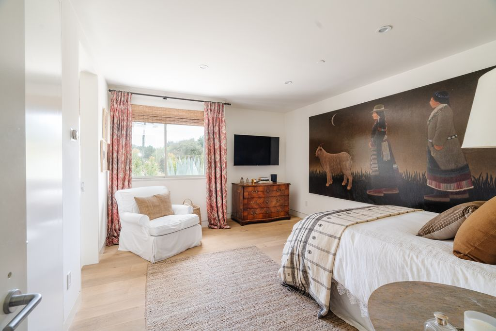 Warm earth tones, textured rugs, and vintage wood furnishings give the space a quieter feel compared to the previous media-driven rooms.